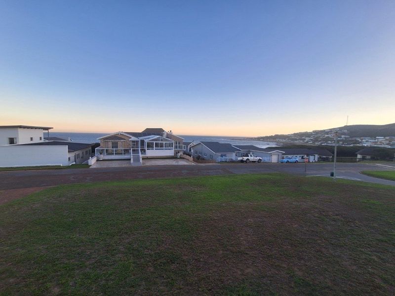 A wide-angle view of the property exterior from the street, showcasing the coastal setting and surrounding neighbourhood landscape.
