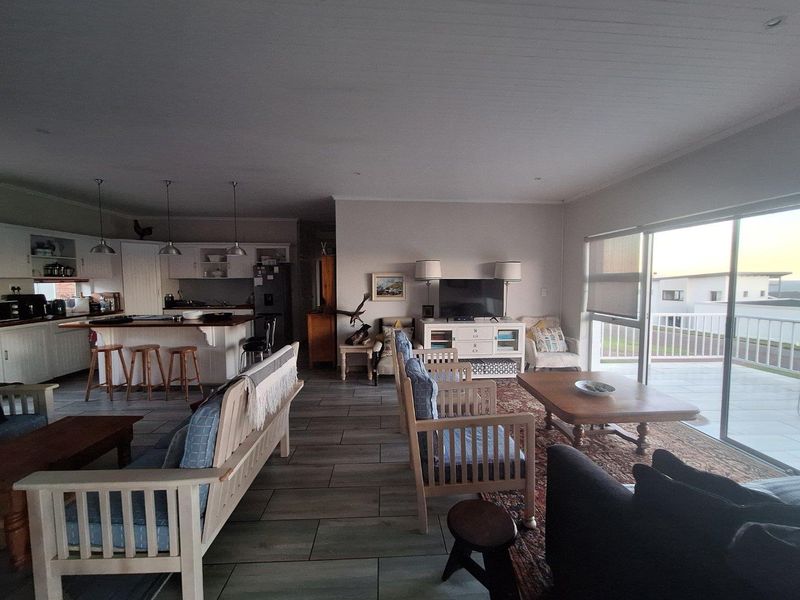 Spacious open-plan living area featuring a modern kitchen with breakfast bar, tiled flooring, and large sliding doors leading to an outdoor balcony.