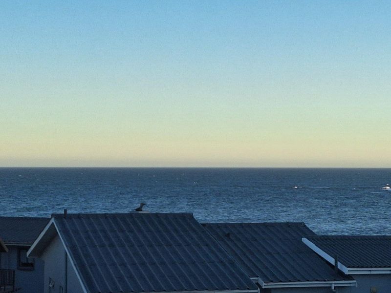 A scenic view overlooking the ocean with residential rooftops in the foreground.