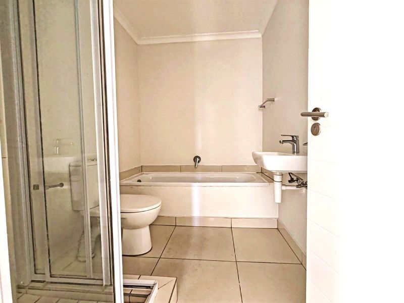 A functional bathroom featuring a built-in bathtub, a separate shower enclosure, a wall-mounted basin, and a toilet with tiled flooring.