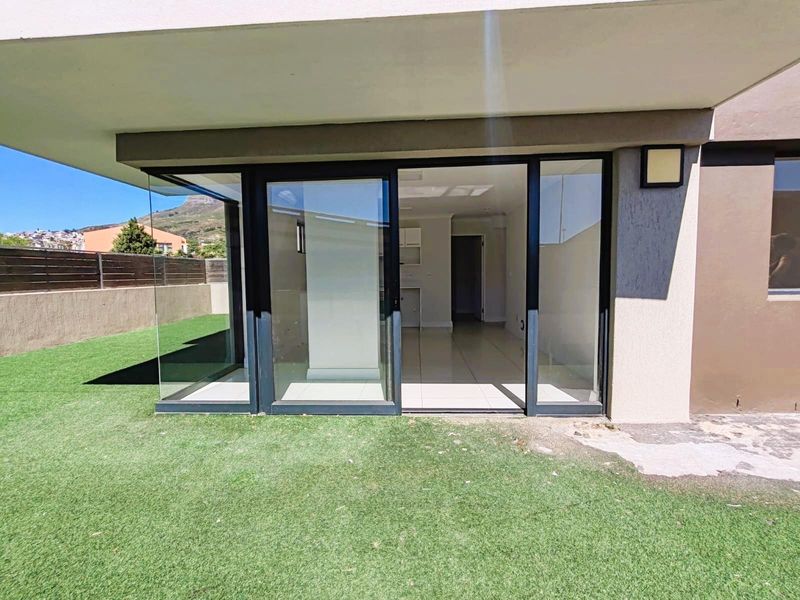 Ground floor apartment featuring a seamless transition from the interior living space to a private garden area through large glass sliding doors.