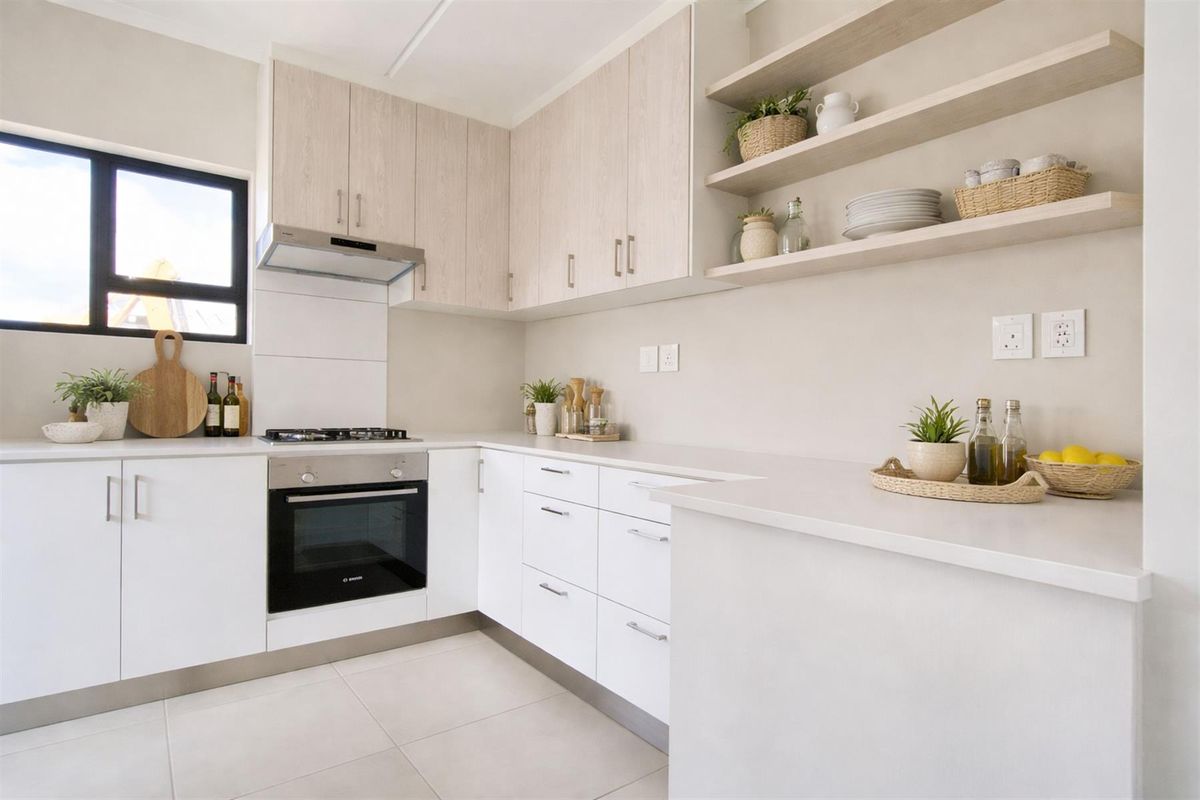 Modern kitchen featuring light wood-toned cabinetry, white countertops, built-in oven, gas hob, extractor fan, and open shelving.