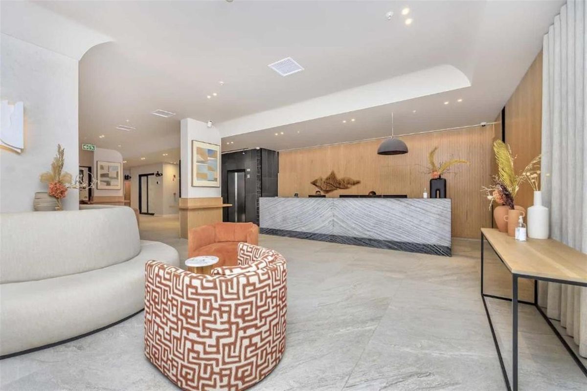 Modern, high-end reception area featuring a stone-clad desk, wood-paneled feature wall, and elegant tiled flooring in a professional building lobby.