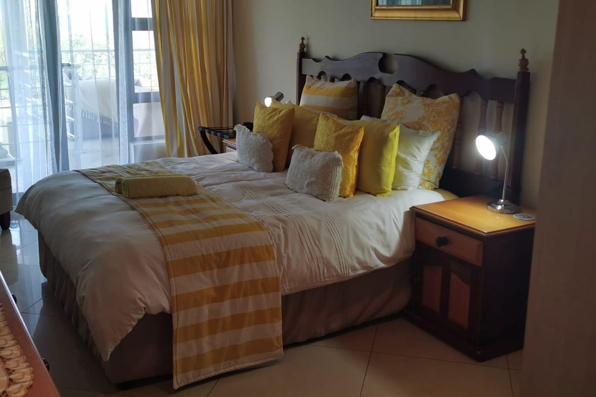 A comfortable bedroom featuring tiled flooring and large sliding glass doors that provide access to an outdoor balcony area.