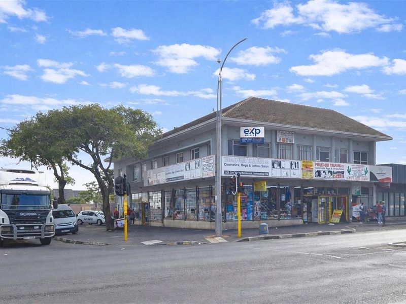 Corner commercial building featuring ground-floor retail storefronts with security grilles and upper-level office or residential space.
