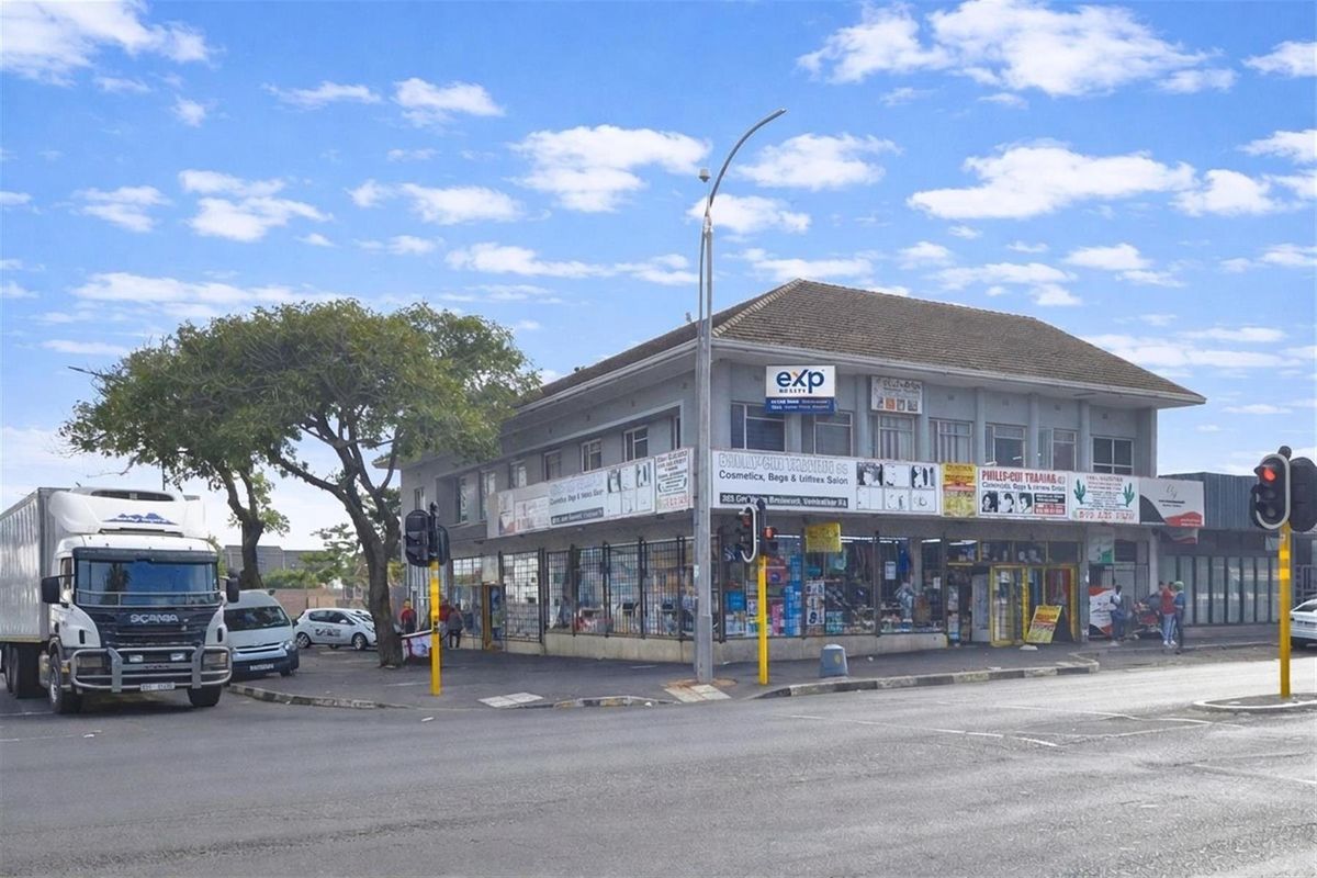 Corner commercial building featuring ground-floor retail storefronts with security grilles and upper-level office or residential space.