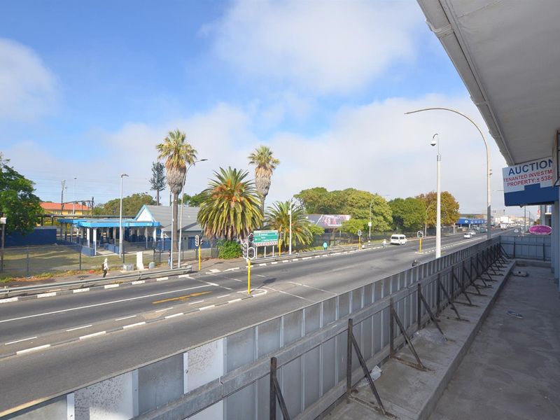 Elevated street view showing the main road, surrounding infrastructure, and commercial frontage with metal safety railings.