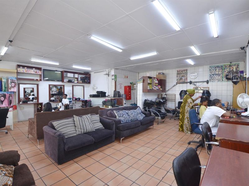Open-plan commercial space currently utilized as a hair salon, featuring tiled flooring, functional lighting, and built-in storage cabinetry.