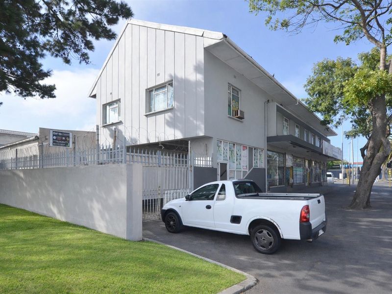Front exterior view of a commercial property featuring a metal security fence, razor wire, and an asphalt driveway.