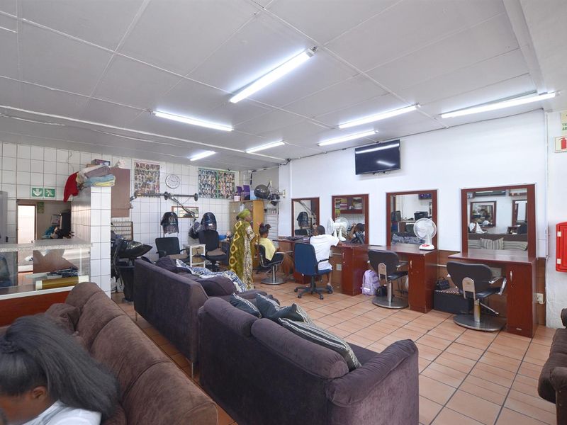 Commercial salon space featuring tiled flooring, built-in vanity stations, and functional fluorescent lighting, suitable for a variety of business operations.