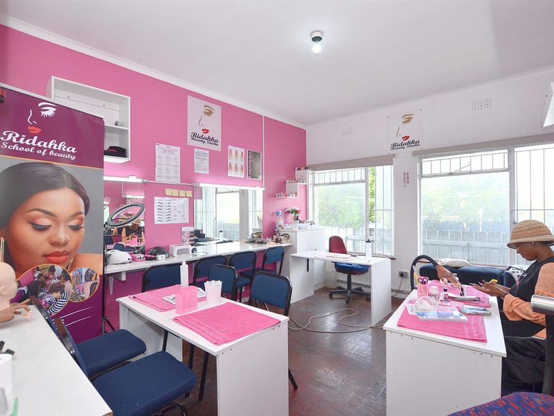 A functional commercial studio space featuring parquet flooring, built-in vanity mirrors, and large windows with security bars, suitable for beauty or professional services.