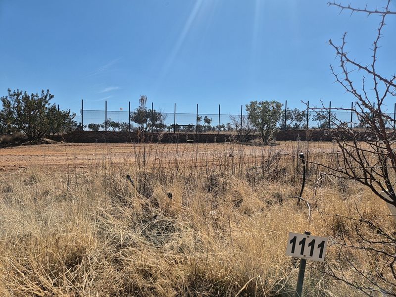 A vacant residential plot featuring a stone retaining wall and perimeter electric fencing, ready for development.