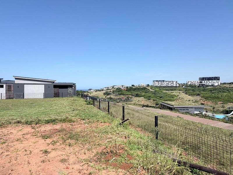 An elevated view overlooking a coastal estate landscape with modern residential architecture and open green spaces.