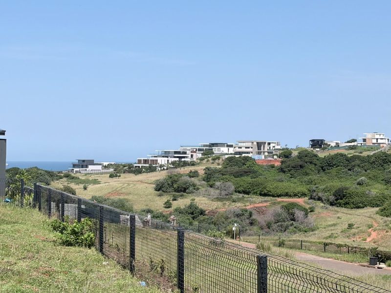 A scenic elevated view overlooking a coastal estate landscape with modern residential properties and natural vegetation.