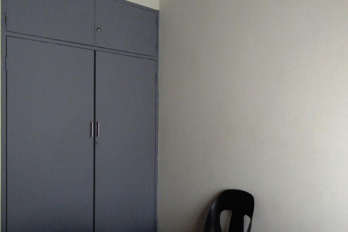 A bedroom featuring built-in grey cabinetry and a ceiling fan, providing functional storage and overhead ventilation.