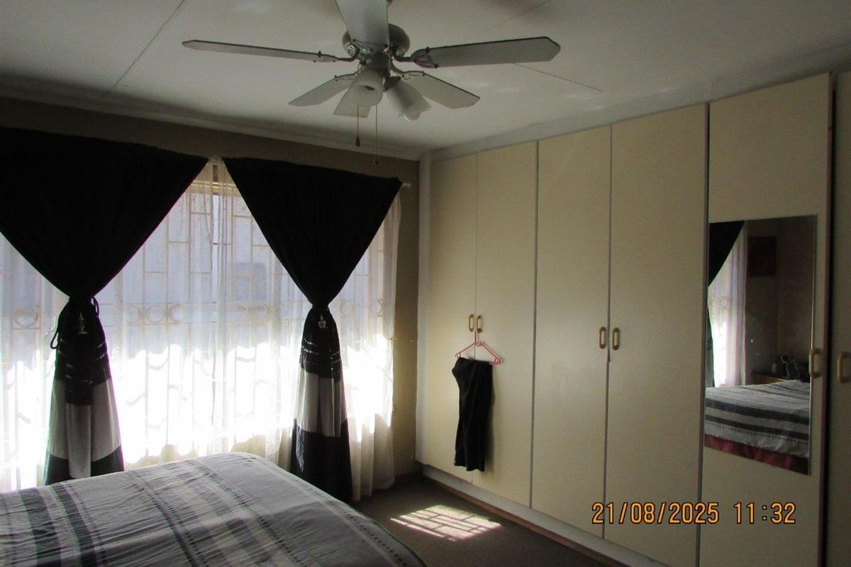 A bedroom featuring built-in floor-to-ceiling cupboards and a ceiling fan, providing functional storage and climate control.