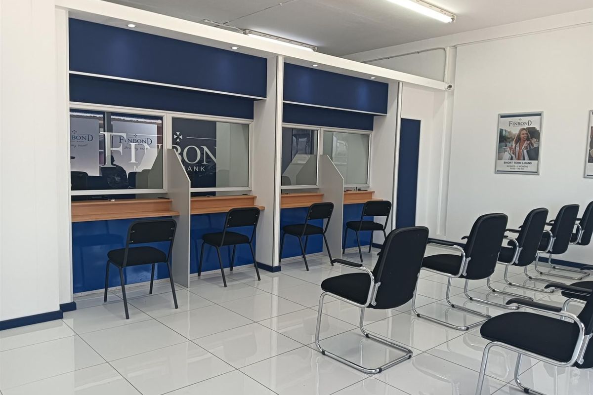 A professional office space featuring built-in service counters with glass partitions, bright tiled flooring, and functional overhead lighting.