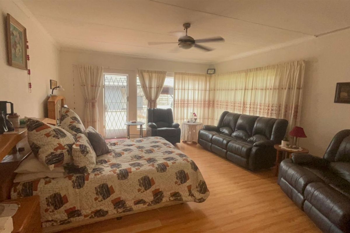 Spacious bedroom featuring laminate flooring, a ceiling fan, and direct access to the exterior through a security gate.