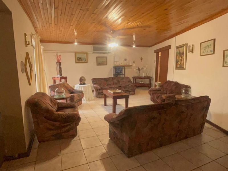 Spacious living room featuring ceramic floor tiles, a timber-clad ceiling, and a wall-mounted air conditioning unit.