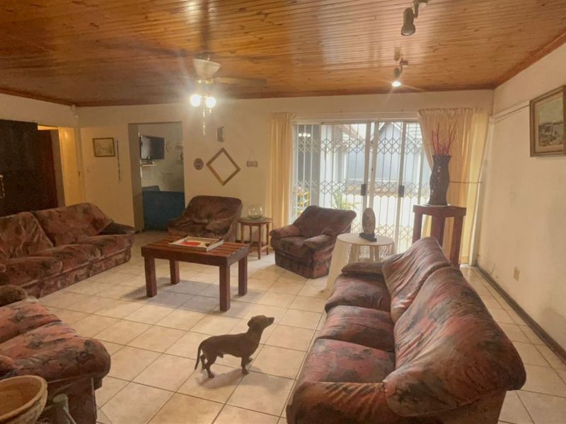 Spacious living room featuring a timber-clad ceiling, tiled flooring, and a sliding glass door with security gate leading to the exterior.