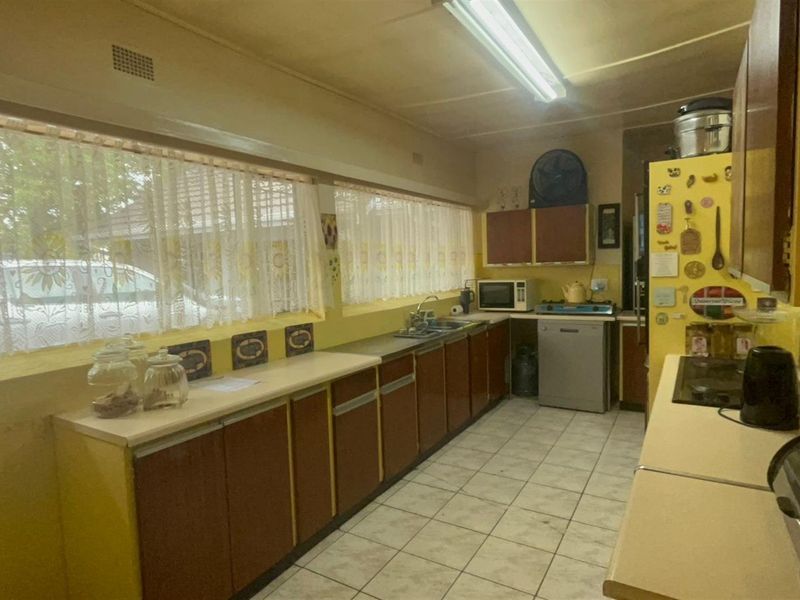 A dated kitchen featuring original cabinetry, laminate countertops, and ceramic tile flooring, offering significant potential for modernization and renovation.