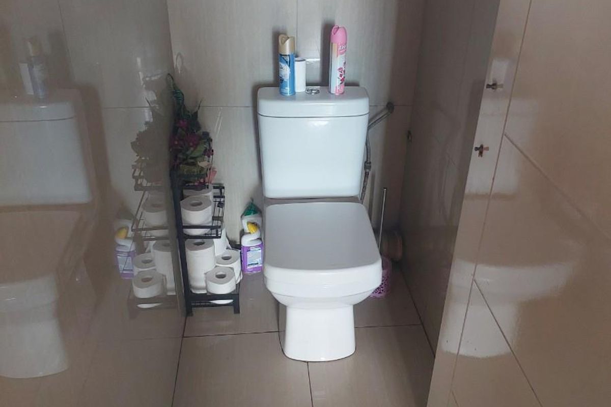 A compact bathroom featuring floor-to-ceiling wall tiles with a decorative mosaic border and a modern white toilet suite.