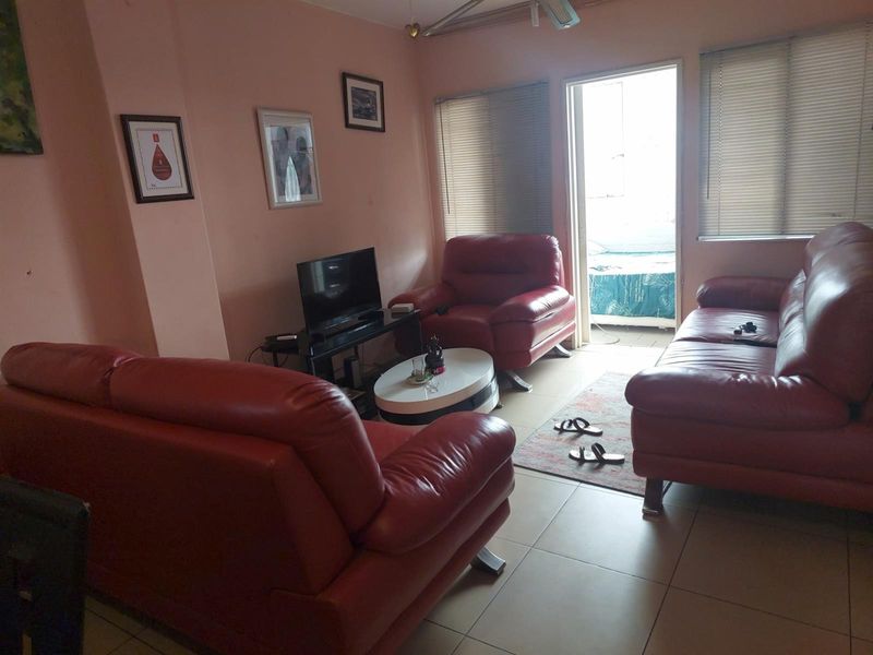 A living room area featuring tiled flooring and direct access to an outdoor balcony space through a glass door.