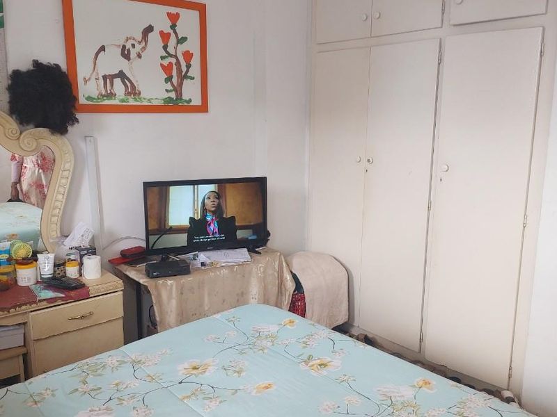 A bedroom featuring built-in floor-to-ceiling cupboards and a ceiling fan.