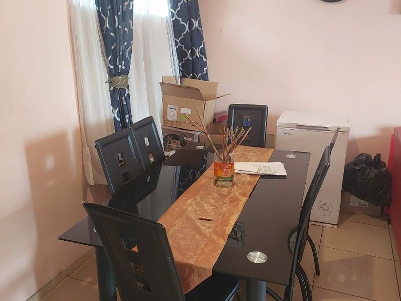 A functional dining area featuring tiled flooring and a window with curtains, providing a practical space for meals.