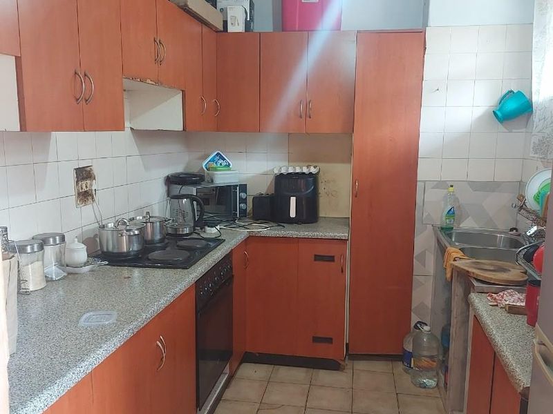 A functional kitchen featuring wood-tone cabinetry, laminate countertops, a built-in oven, and a tiled floor, offering a practical layout for daily meal preparation.