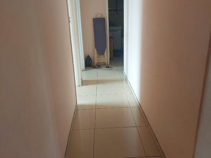 A functional apartment hallway featuring neutral floor tiles and access to adjacent rooms.