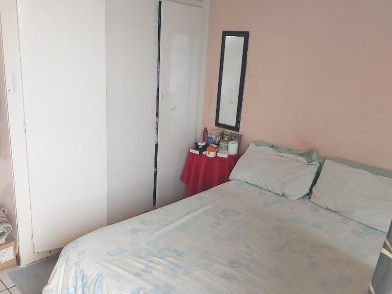 A bedroom featuring built-in floor-to-ceiling cupboards and tiled flooring.