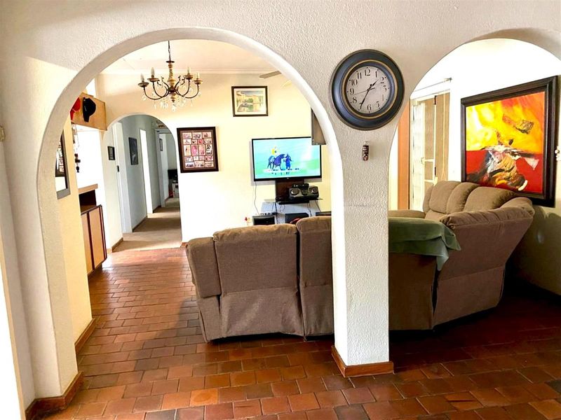 Living room featuring terracotta tile flooring and distinctive arched doorways connecting to the hallway and adjacent living spaces.