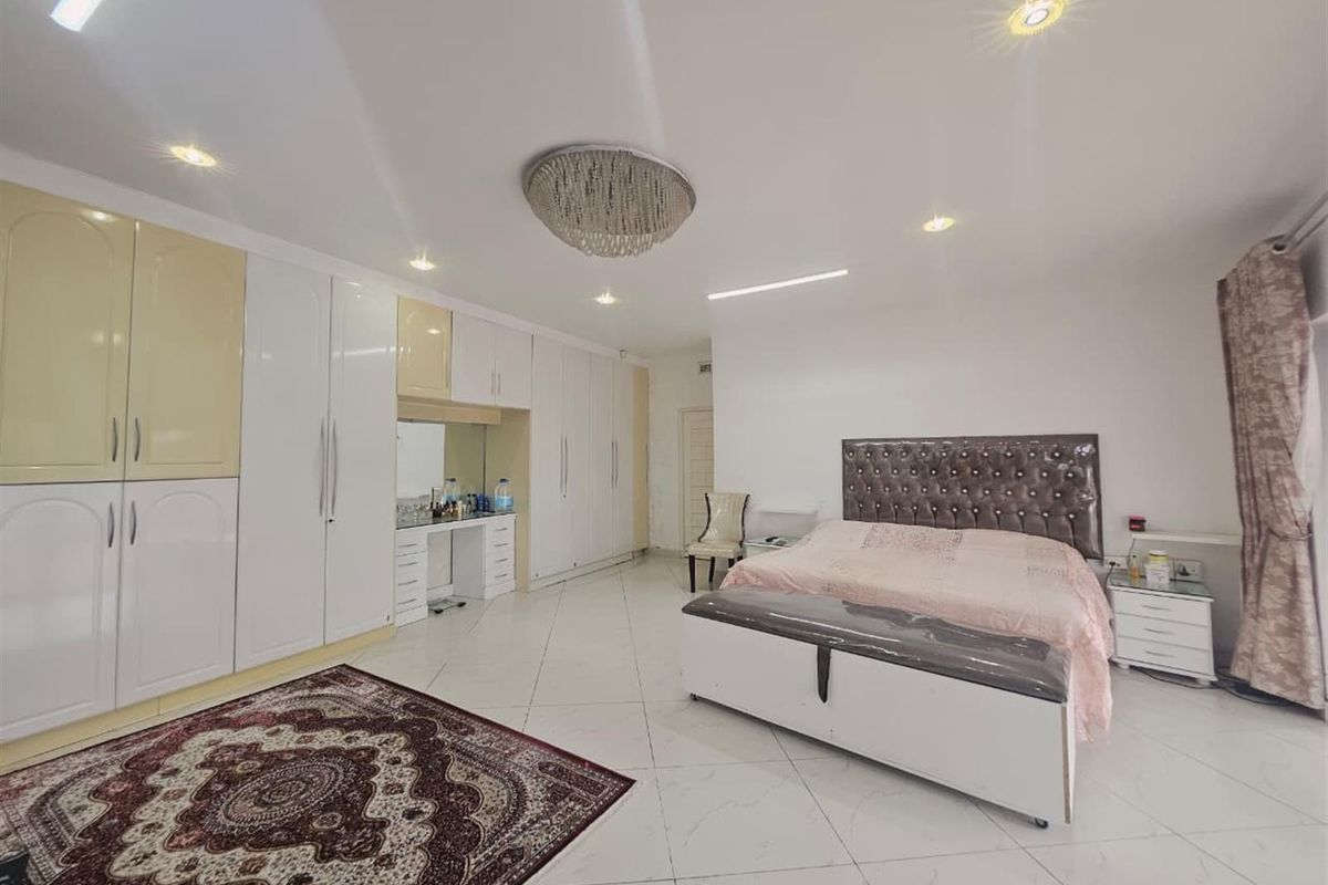Spacious bedroom featuring extensive built-in cabinetry with integrated vanity, recessed ceiling lighting, and polished tile flooring.
