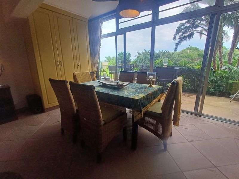 Dining area featuring built-in cabinetry, tiled flooring, and large sliding glass doors providing direct access to the outdoor patio and garden.