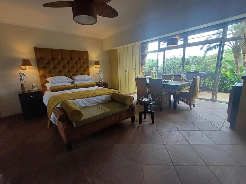Spacious bedroom featuring tiled flooring, built-in cupboards, and large sliding glass doors providing natural light and access to the outdoor area.