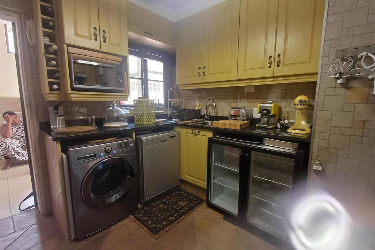A compact kitchen featuring yellow cabinetry, granite countertops, tiled backsplash, and integrated appliance spaces.