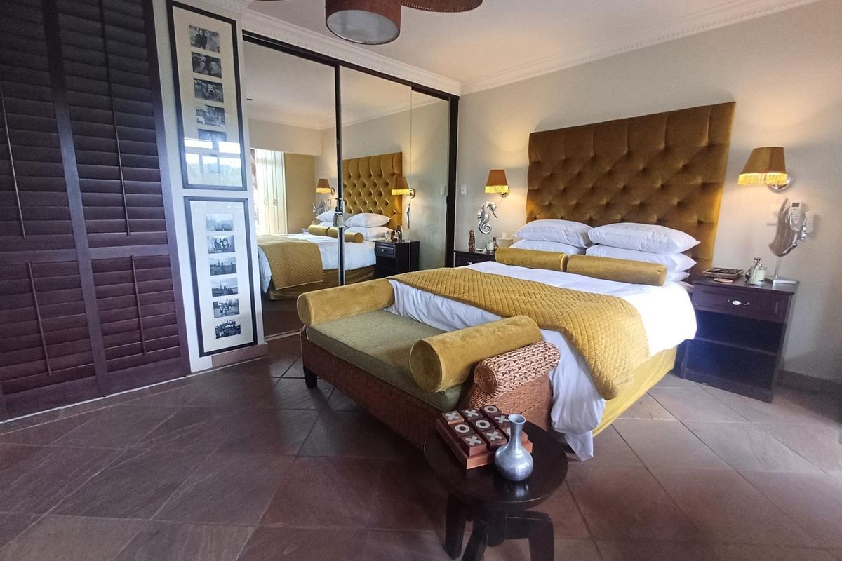 Spacious bedroom featuring stone tile flooring, crown molding, a ceiling fan, and large mirrored sliding wardrobe doors.