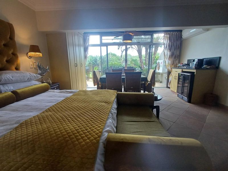 Open-plan bedroom and kitchenette area featuring tiled floors, built-in cabinetry, and large sliding doors opening to an outdoor patio space.