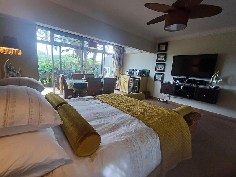 Spacious bedroom featuring a ceiling fan, air conditioning, and large sliding glass doors providing access to an outdoor patio area.