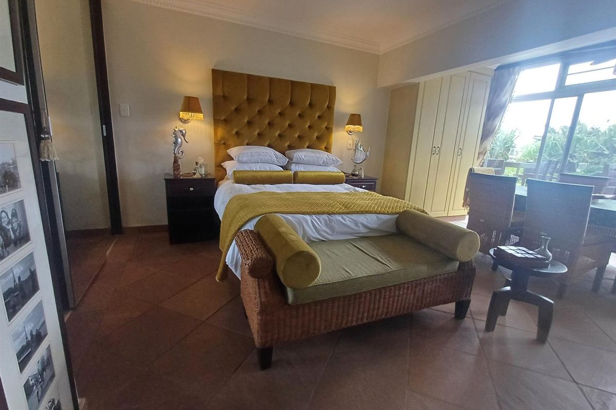 A well-maintained bedroom featuring terracotta floor tiles, built-in cupboards, and direct access to a balcony through sliding glass doors.