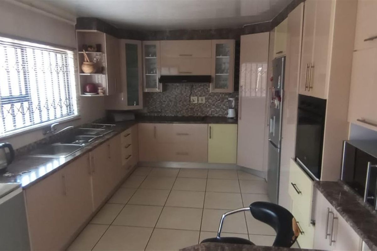 A functional kitchen featuring light-toned cabinetry, tiled flooring, a built-in oven, and a mosaic tile backsplash.