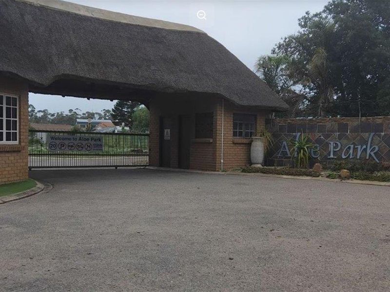 The entrance gatehouse to Aloe Park, featuring a traditional thatched roof, brick facade, and secure gated access.