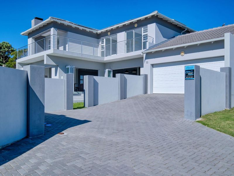 Modern double-story townhouse featuring a paved driveway, double garage, and an upper-level balcony with contemporary architectural finishes.
