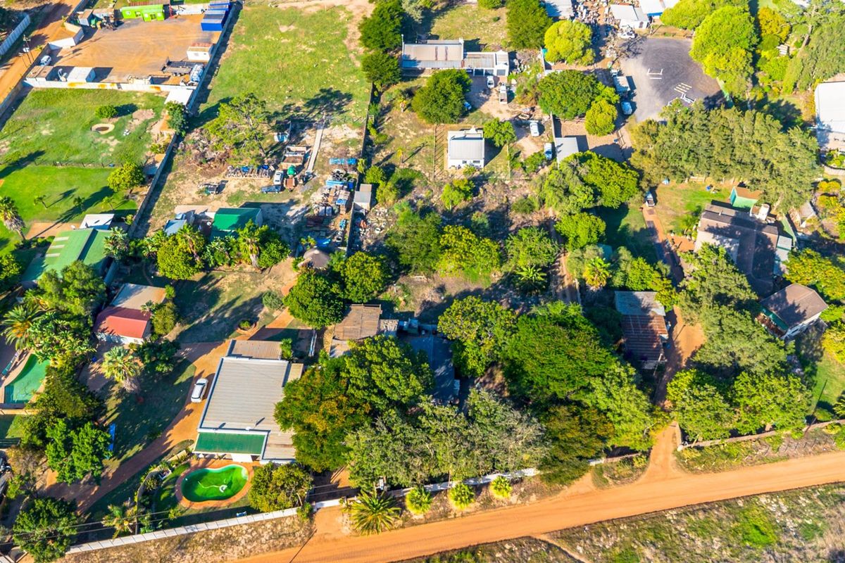 Aerial view of a small holding property featuring multiple structures, mature trees, a swimming pool, and extensive outdoor space.