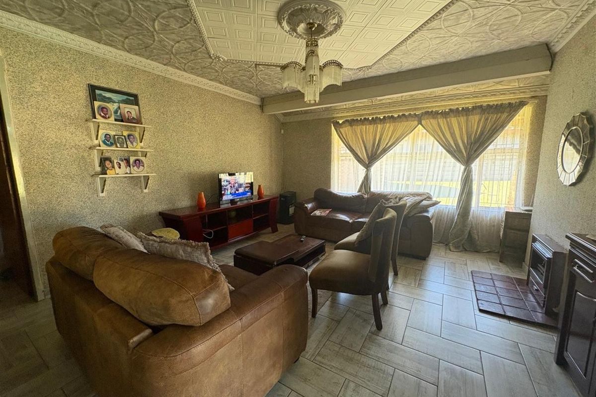 A living room featuring tiled flooring, a built-in fireplace, and decorative ceiling tiles with a central chandelier.