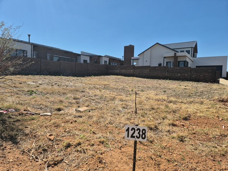 A vacant residential plot featuring a brick boundary wall and clear lot identification marker, ready for development in a residential estate.