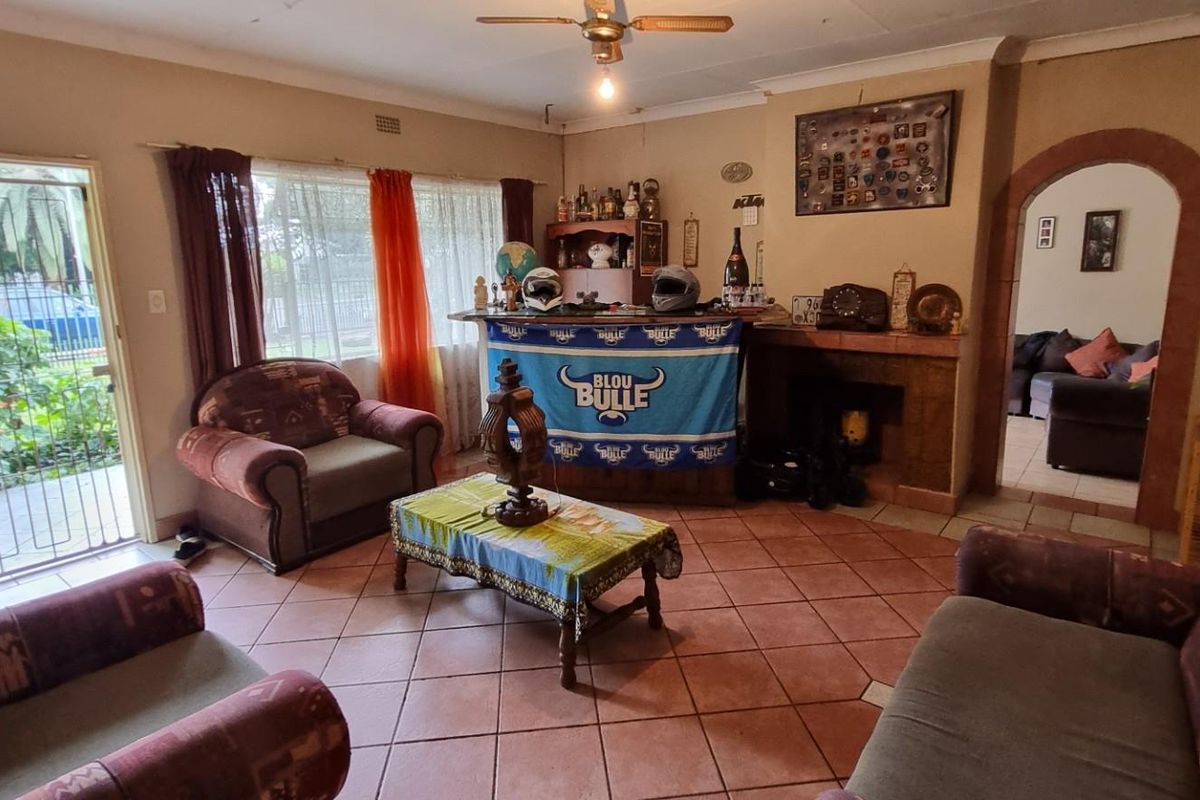 A living room featuring terracotta floor tiles, a built-in bar area, and an arched doorway leading to an adjacent living space.