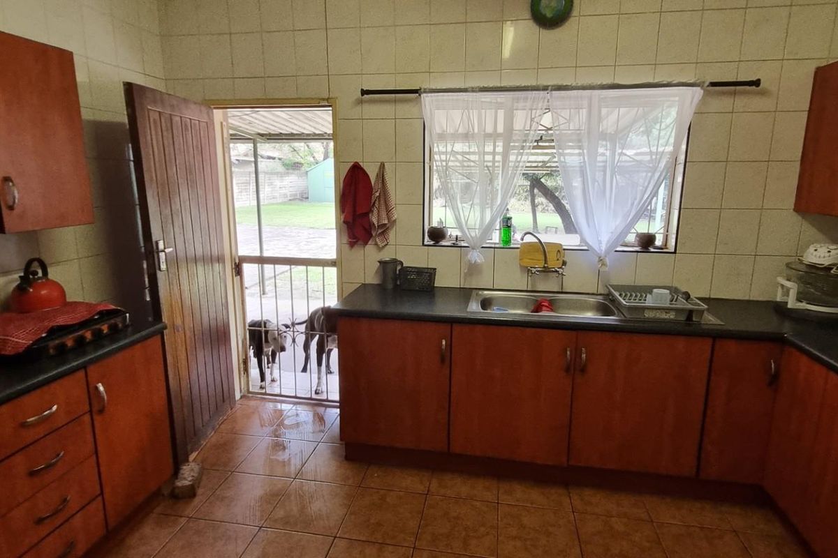 Functional kitchen featuring wooden cabinetry, dark countertops, tiled splashbacks, and direct access to the rear outdoor area.