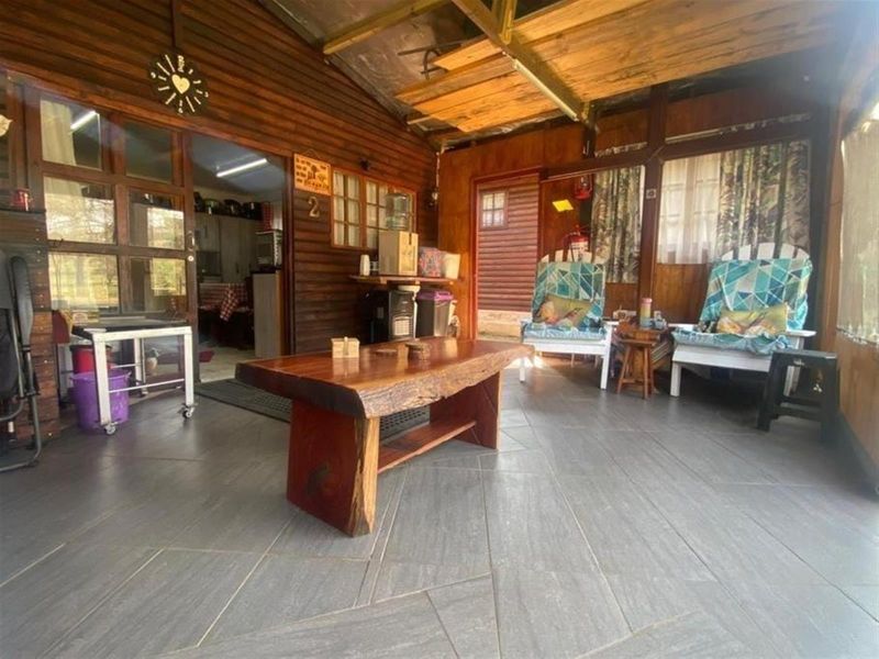 A rustic covered patio area featuring timber wall cladding, tiled flooring, and a corrugated roof, providing a sheltered outdoor living space.